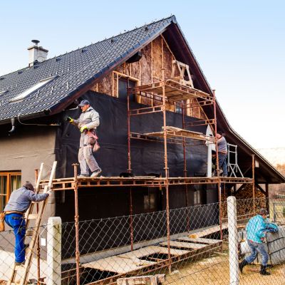 Construction workers thermally insulating house with glass wool